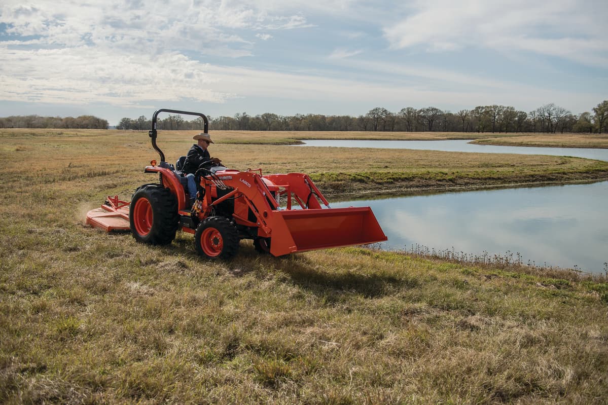 man mowing by water with grand l60
