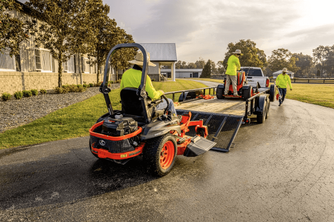 Fleet of mowers driving onto the back of trailer