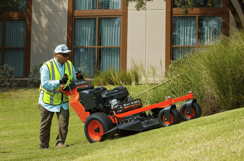 Landscaper pushing mower up hill