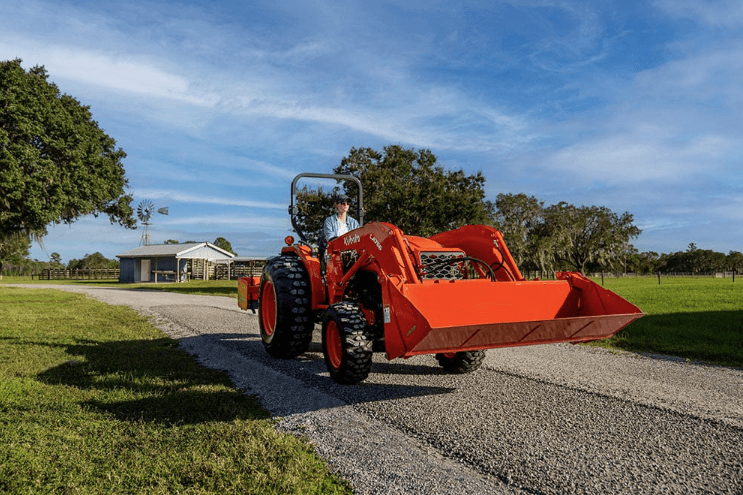 Woman driving tractor down a gravel driveway