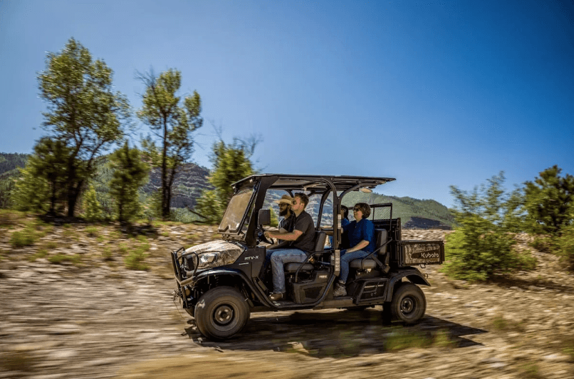 A person driving an RTV with three passengers