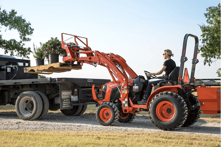 Woman using tractor to load a pallet of flowers onto a trailer