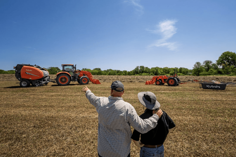 Men looking at tractors doing hay production