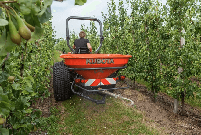 Tractor pulling spreader through narrow rows