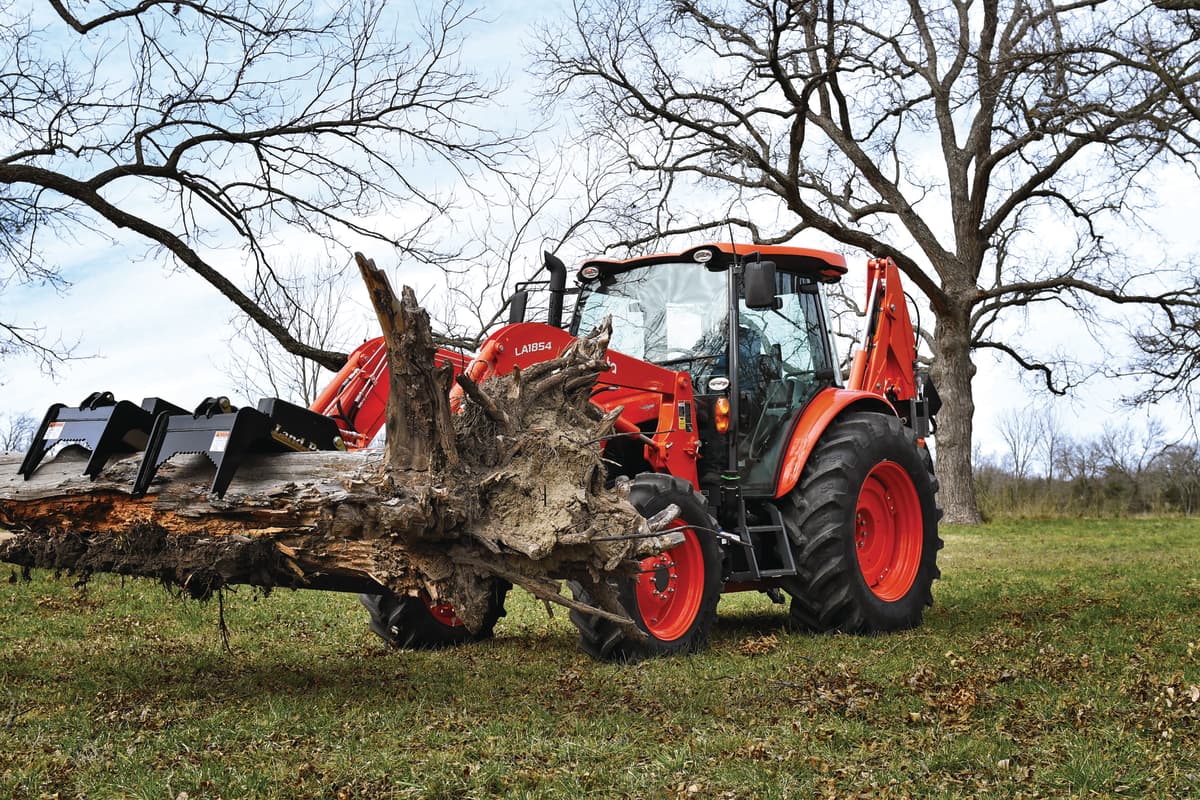 Kubota M5 moving a tree with claw grapple